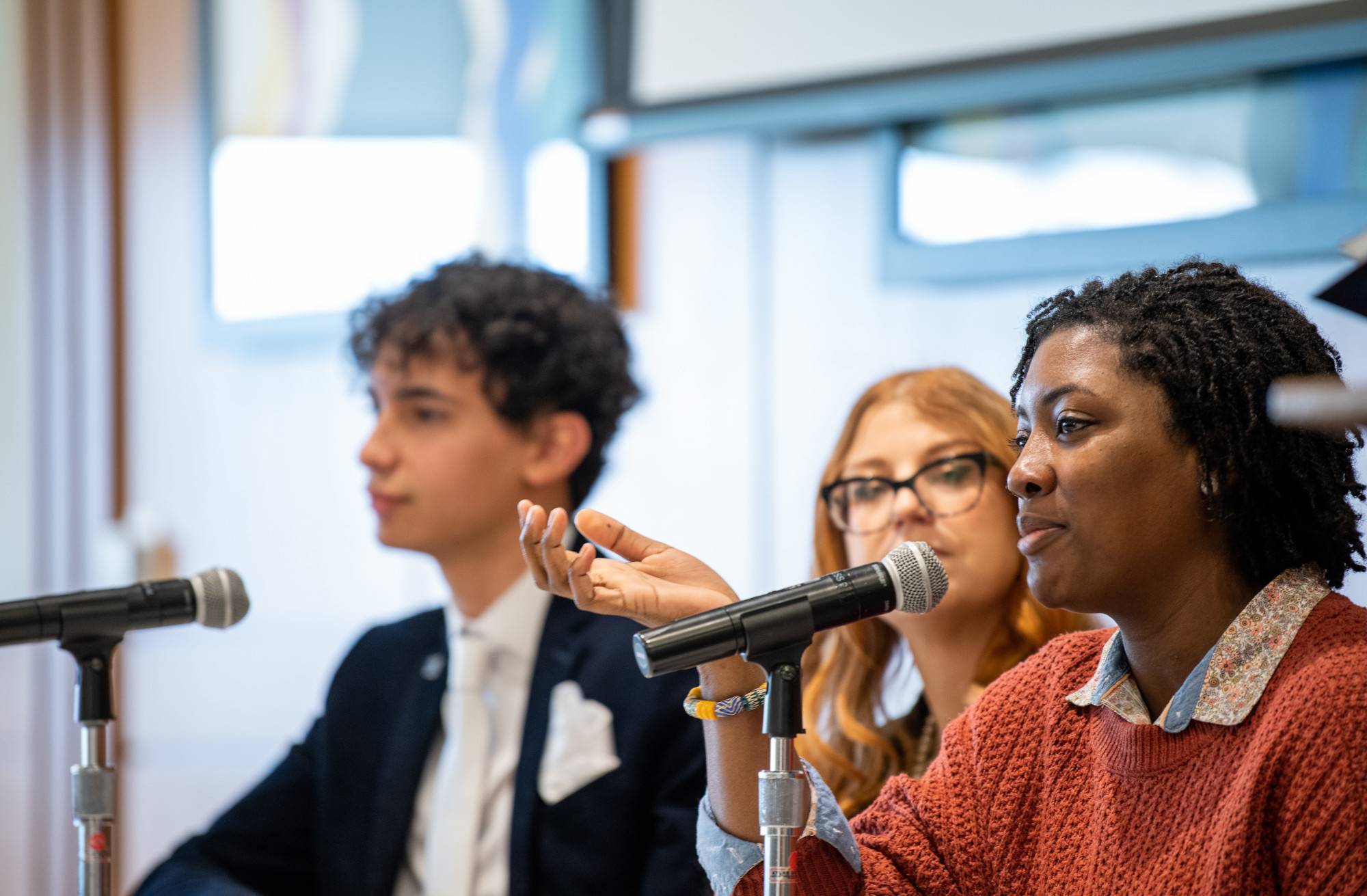 Three students sitting at a panel table answering questions